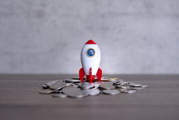 Closeup image of rocket spaceship and coins. Business startup, launch and boost concept.
