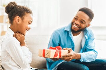African-american father giving gift to daughter at home