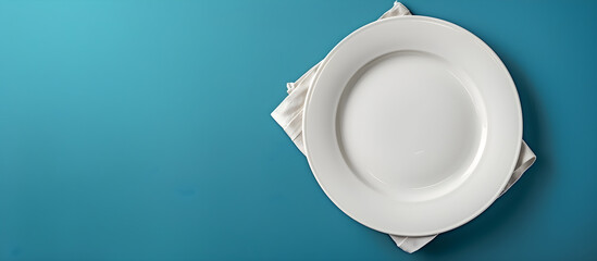 An empty white plate and a cotton napkin on a blue background, suitable for a menu or recipe book.