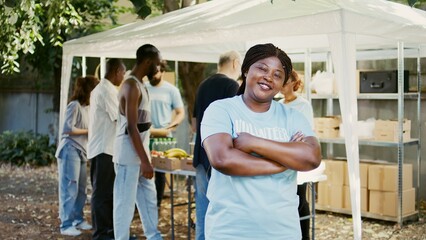 African American female volunteer grins and poses during a food drive charitable event....