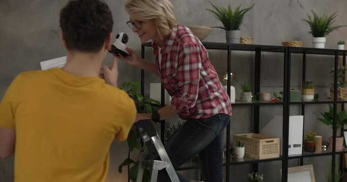 Mother and son adjust and install home cctv video surveillance camera
