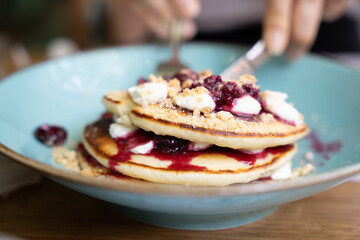 Close-up of pancakes with berry compote and cream on a blue plate