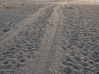Rut in the sand. Tracks from car wheels on the beach. Sand and stones.