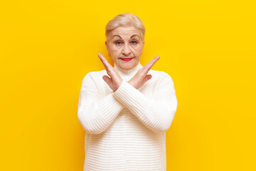 old grandmother in a white sweater shows a stop gesture with her arms crossed and prohibits on a...