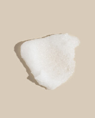 White sugar scrub smear smudge swatch on beige background. Natural cosmetic skin exfoliation product sample