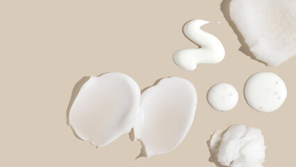 Composition of various cosmetic scrub, creams, serum and lotion smear on a beige background. Beauty...