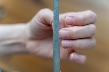 Woman's hands doing manicure treatment, filing nails with a nail file