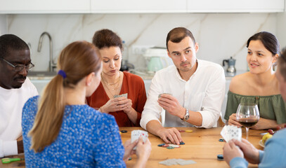 Young man deeply engrossed in friendly poker game with group of friends of different nationalities...
