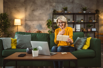 one mature woman open box presents and read card while on video call