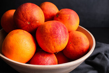 Side View of Blood Oranges in a Bowl: Several whole raspberry oranges in a large bamboo wood bowl