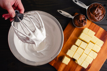 Hand Holding a Stand Mixer Whisk Attachment Covered in Meringue: Woman's hand holding a wire whip...