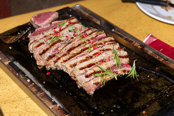 beef steak with pink pepper and rosemary cooked on stone