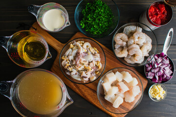 Prepped and Thawed Seafood Soup Ingredients on Cutting Board: Chopped and measured fish, shrimp,...