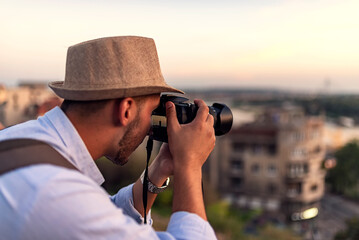 Handsome Young Man with Backpack and Hat on Travel Taking a Photos of the City