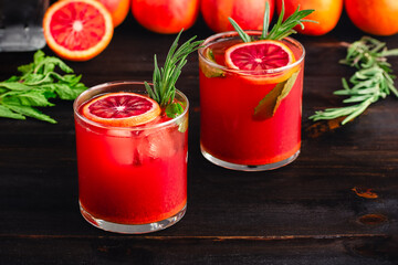 Sparkling Blood Orange Mocktails Garnished with Fresh Herbs: Mocktails with citrus juice, ginger, turmeric, rosemary, and mint in rocks glasses