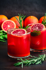 Sparkling Blood Orange Mocktails Garnished with Fresh Herbs: Mocktails with citrus juice, ginger, turmeric, rosemary, and mint in rocks glasses