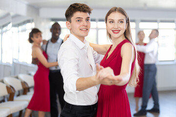 Fototapeta na wymiar Energy man and young woman are dancing classic version of waltz in couple during lesson at studio. Leisure activities and physical activity for positive people.