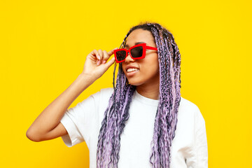 young african american woman with hipster colored dreadlocks and sunglasses on yellow isolated background, girl with unique purple hairstyle looking away wearing glasses - Powered by Adobe