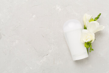 Cosmetic bottle with flowers on concrete background, top view