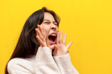 young asian girl with braces shouts loudly and announces information on a yellow isolated...