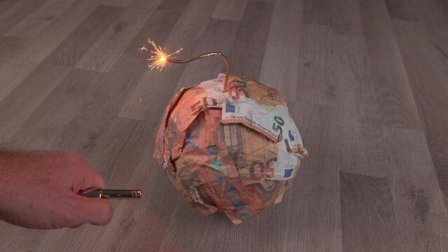 Bomb from Euro banknotes with a burning wick, on a wooden floor. The concept of financial crisis, loss of money, bankruptcy