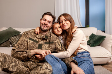 military man of the Ukrainian army in camouflage uniform returned home and hugs his family, soldier...