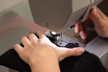 Foto próxima de mão feminina ajustando tecido na máquina de costura