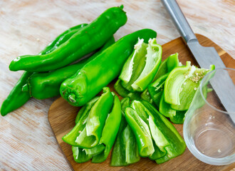 Sweet green bell pepper sliced on wooden cutting board, prepared for cooking