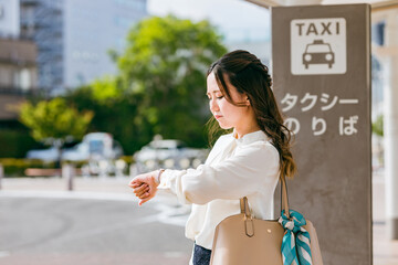 タクシー乗り場でタクシーを待つビジネスウーマン（遅い・遅刻・イライラ）
 - obrazy, fototapety, plakaty