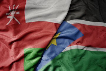 big waving national colorful flag of south sudan and national flag of oman.