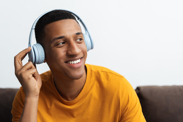 Portrait of smiling overjoyed African American man wearing headphones, listening to music