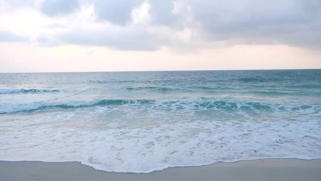 Gray cloudy in the morning and sea waves roll onto the sand.