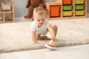Children toys. Cute little boy and spinning top on rug at home