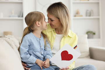 Little daughter congratulating her mom with greeting card at home. Happy Mother's Day