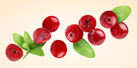 Fresh red cranberries and green leaves flying on beige background