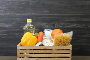 Crate with donation food against wooden background, closeup