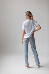 Beautiful blonde woman in a white T-shirt and blue jeans posing on a white background