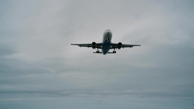 Airplane in slow motion against a background of cloudy weather.