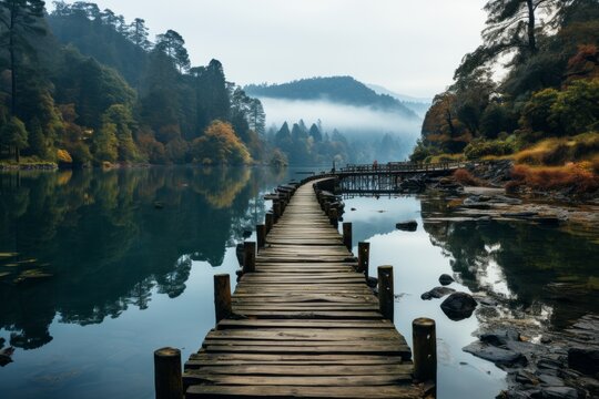 Wooden bridge across lake with trees and mountains in natural landscape