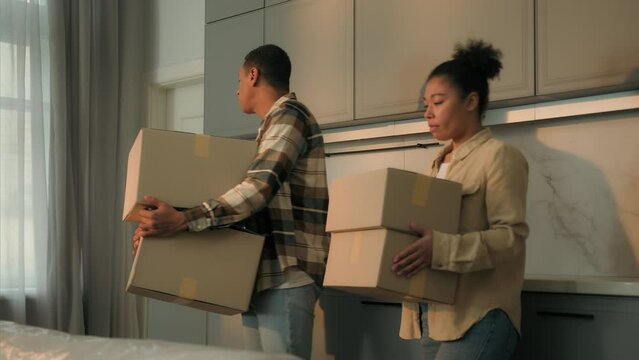 Sad upset couple African American family renters tenants leave home with cardboard boxes relocation moving day disappointed frustrated man woman move out apartment mortgage debt eviction sale house