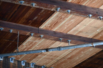 Wooden support beams under bridge with fire sprinkler lines.