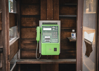 Old public telephone installed in a wooden box in Japan.