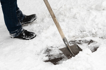 A skilled worker efficiently clears snow using an iron shovel with a sturdy wooden handle....