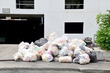 BANGKOK, THAILAND - March 21, 2024: Lots of pieces of garbage in clear and black plastic bags, piled up outside. front of building. Concept pollution problems in Thailand.
