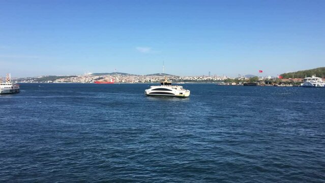 A ferry passing by in the distance on the Bosporus in Istanbul Turkey. The weather is beautiful, the sun is bright, the famous skyline is visible with the ship in the distance moving along.