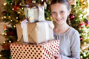 Child with holiday presents in front of Christmas Tree