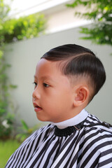 Cutting hair of Asian little boy with barber scissors in the garden. - 761951169