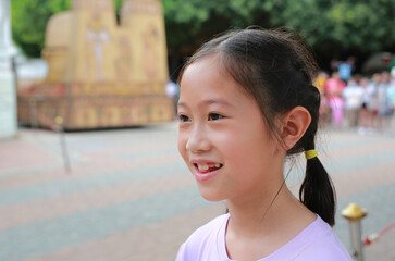 Close up of smiling Asian girl in the garden. Portrait of kid side view. - 761951362