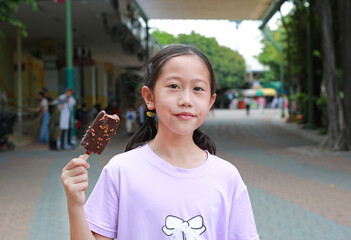 Asian girl child eating ice cream outdoors in the garden. Kid with delicious icecream. - 761951365