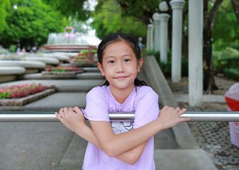 Portrait of Asian girl child enjoy to climbing aluminum fence in public park. - 761951372